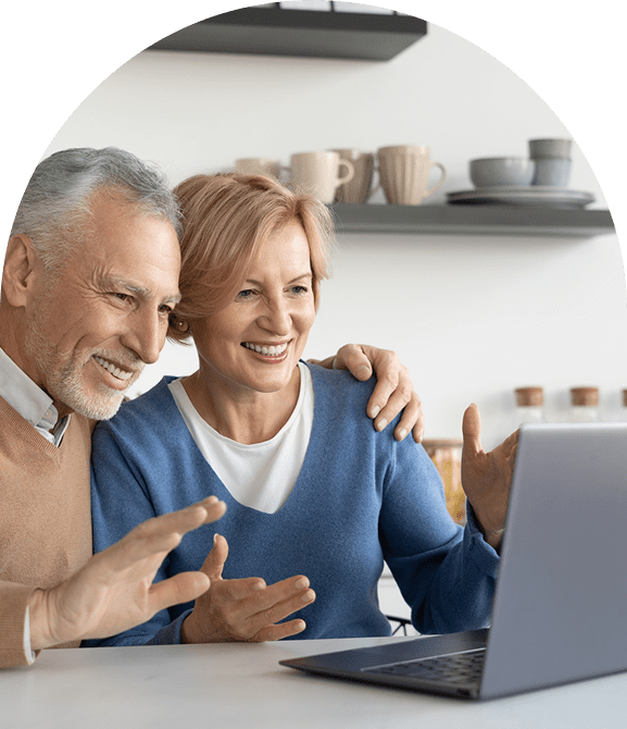 Older couple smiling at laptop screen.