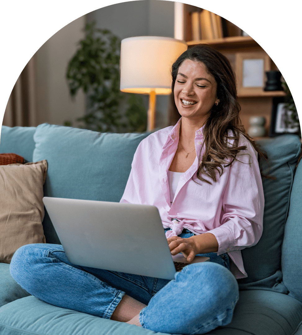 Woman smiling while using a laptop, seated.